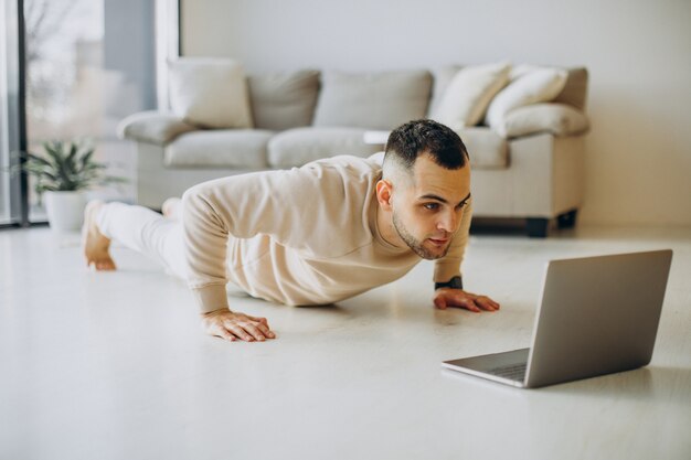 Young sporty man practicing yoga at home