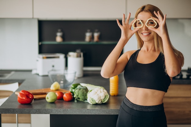 Free Photo young sporty woman with pepper at the kitchen