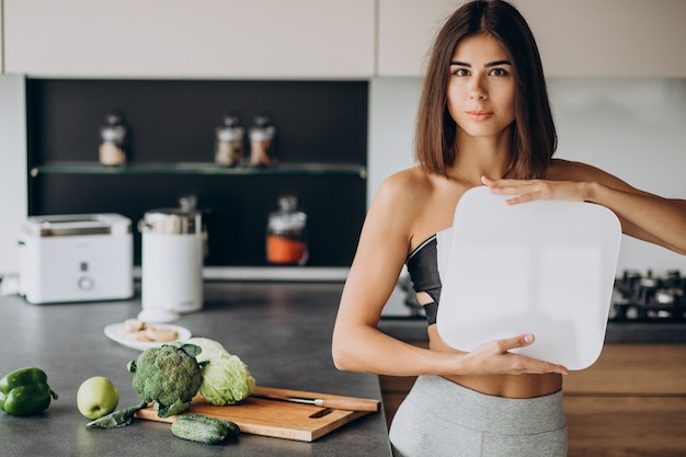 Free Photo young sporty woman with scales at kitchen