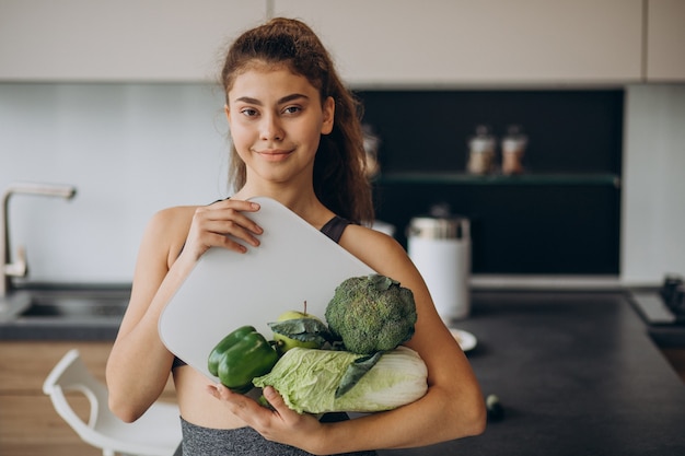 Free Photo young sporty woman with scales and vegetables at the kitchen