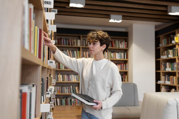 Young student looking for a book in the library