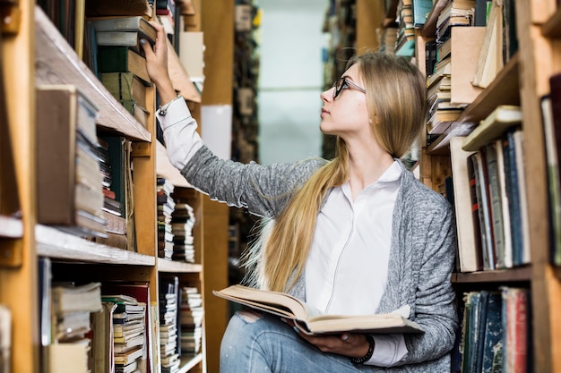 Young student picking books from bookshelf