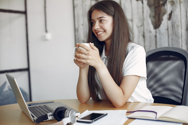 Young student sitting at the table and use the laptop