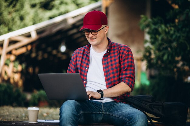 Young student working on a computer outside the cafe in park