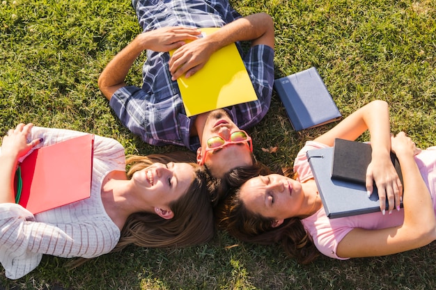 Young students with books posing on grass