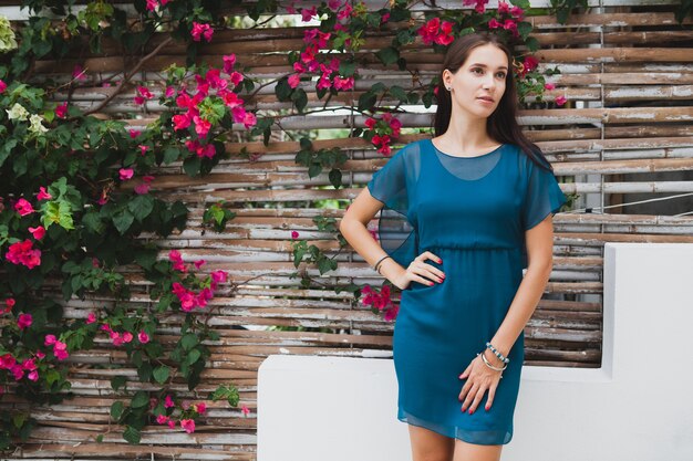 Young stylish beautiful woman in blue dress, summer fashion trend, vacation, garden, tropical hotel terrace, smiling