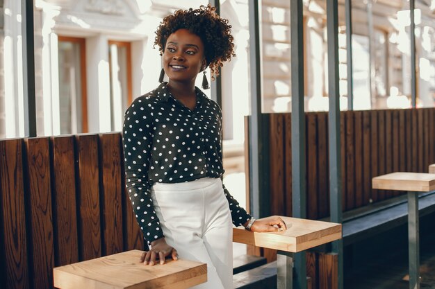 A young and stylish dark-skinned girl standing in a sunny city