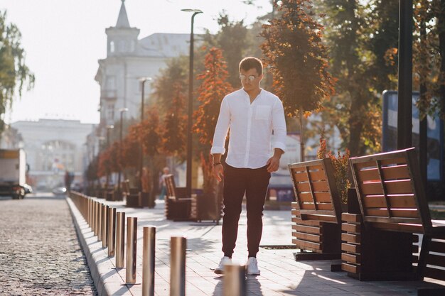 Young stylish guy in a shirt walking down a European street on a sunny day