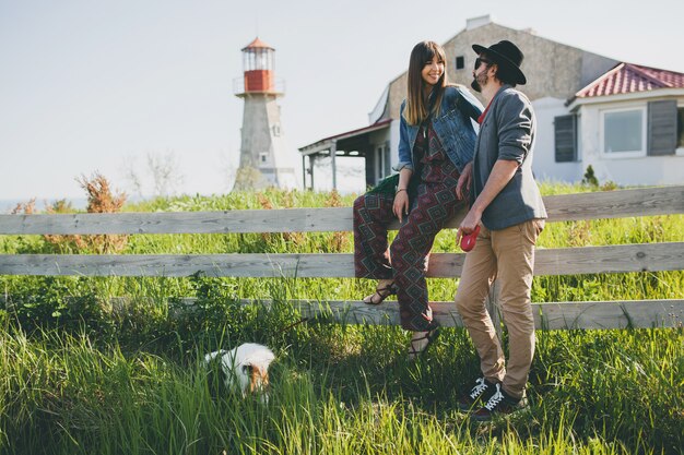 Young stylish hipster couple in love walking with dog in countryside