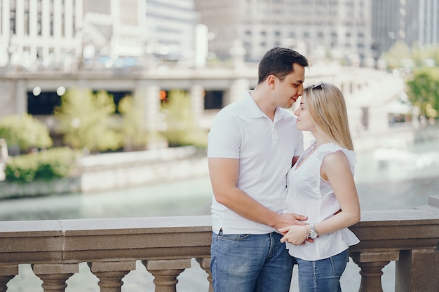 young and stylish lovers couple in white t-shirts and blue jeans standing in a big city 