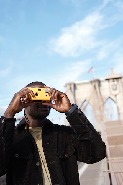 Young stylish male photographer using camera while exploring the city