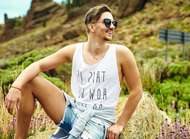 Free photo young stylish man in casual hipster clothes posing on nature