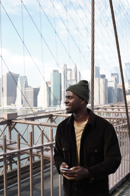 Young stylish man exploring a city bridge by himself