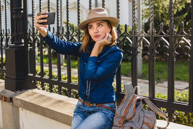 Young stylish pretty woman taking a selfie, dressed in denim shirt and jeans