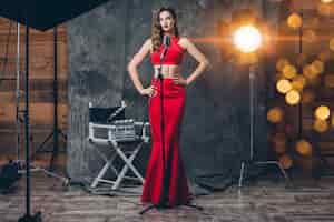 Free photo young stylish sexy woman on cinema backstage, celebrating, red satin evening dress