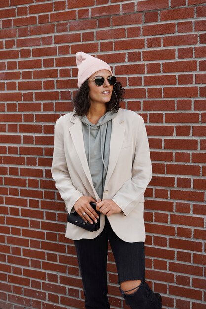 Young stylish woman posing against brick wall in the city