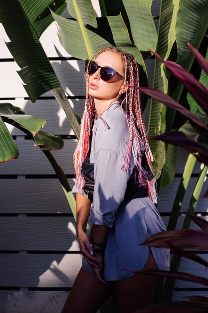 Young stylish woman with pink purple braids and black waist bag posing outdoor