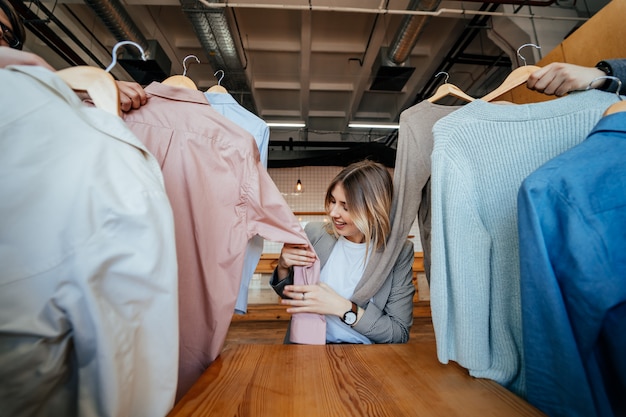 Young stylist looking through set of shirts for fashion shooting