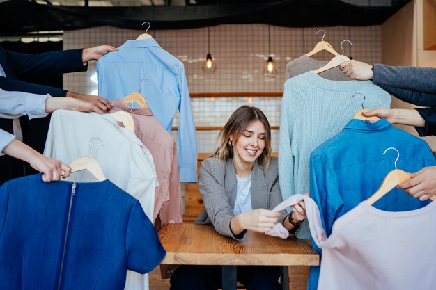 Young stylist looking through set of shirts for fashion shooting