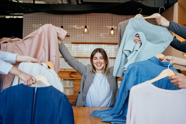 Young stylist looking through set of shirts for fashion shooting