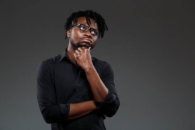 Young successful african businessman in glasses posing on dark