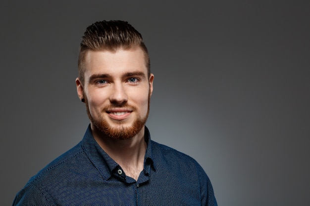 Young successful businessman posing over dark wall.