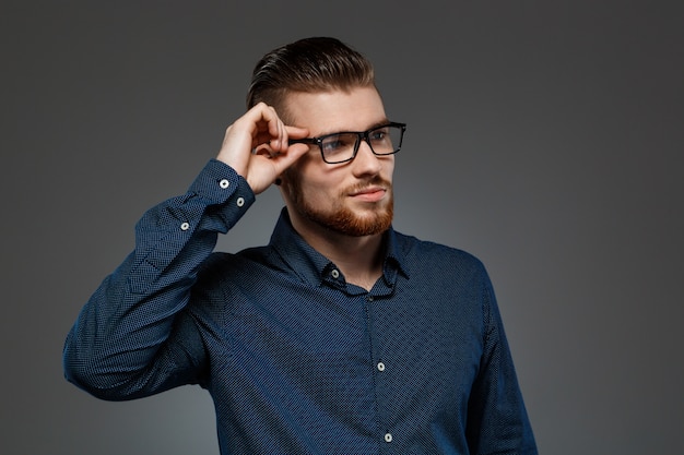 Free photo young successful businessman posing over dark wall.