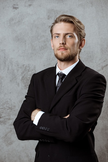 Free photo young successful businessman posing with crossed arms