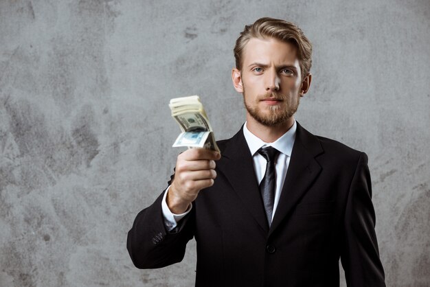 Young successful businessman in suit holding money