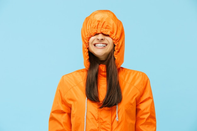 The young surprised couple at studio in autumn jackets isolated on blue.