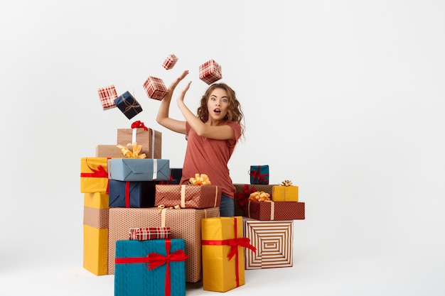 Free Photo young surprised curly woman among lying and falling gift boxes