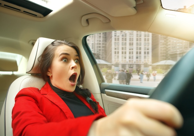 Young surprised woman driving a car