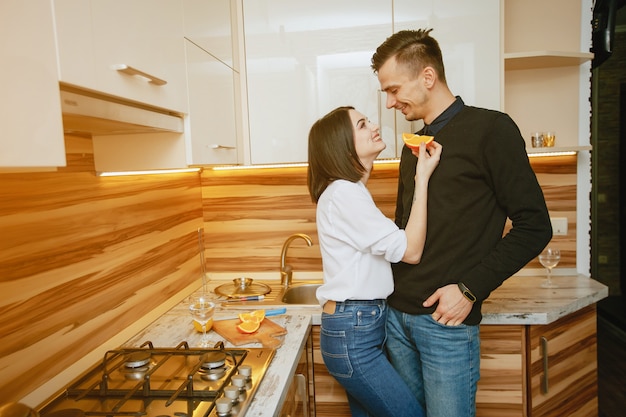 young and sweet lovely couple standing in the kitchen with orange