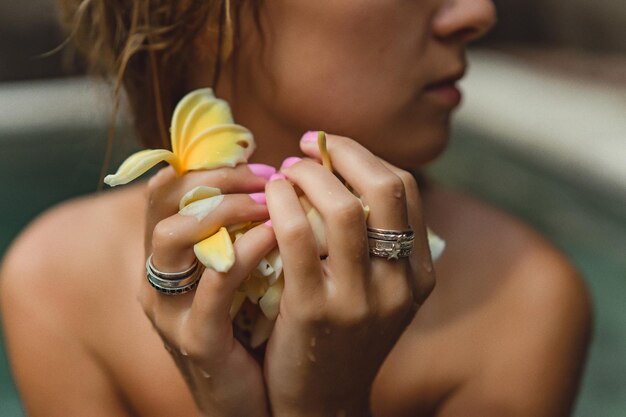 young tanned woman in the pool in frangipani flowers