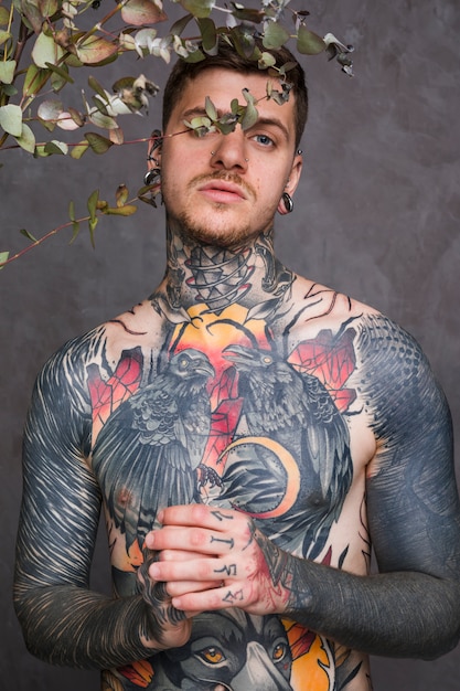 Free Photo young tattooed man with piercing in his nose and ears looking to camera