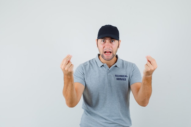 Free photo young technician doing italian gesture, being displeased with dumb question in grey uniform.