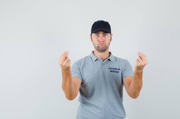 Young technician doing italian gesture in grey uniform and looking puzzled.