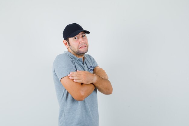 Young technician in grey uniform feeling cold and hugging himself.