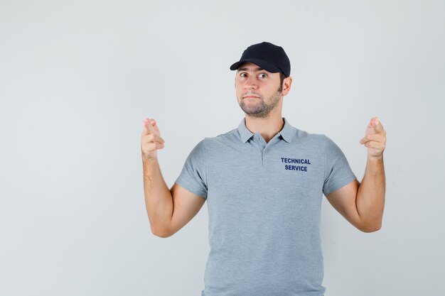 Young technician making finger pistol sign in grey uniform and looking confident.