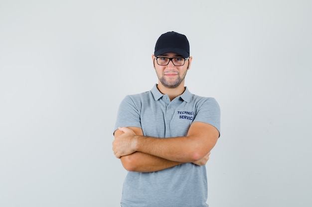 Free Photo young technician standing with crossed arms in grey uniform and looking confident.