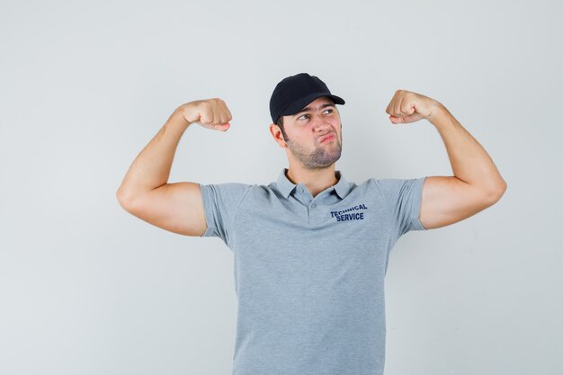 Young technician in uniform showing muscles of arms and looking confident.