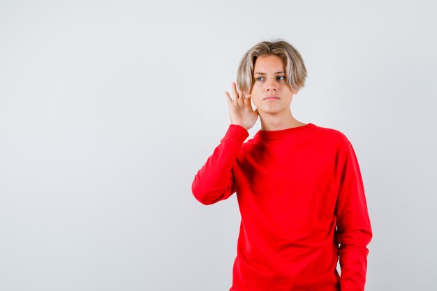 Young teen boy overhearing private conversation in red sweater and looking confused. front view.