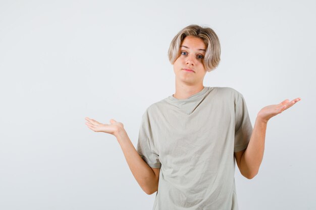 Young teen boy showing helpless gesture in t-shirt and looking confused , front view.