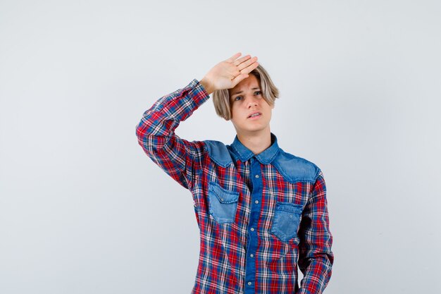 Young teen boy with hand on head