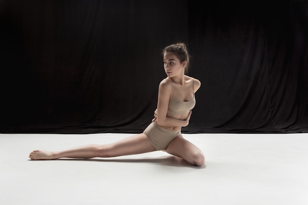 Young teen dancer dancing on white floor studio background. Ballerina project.