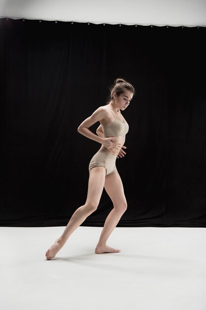 Young teen dancer dancing on white floor studio background. Ballerina project.