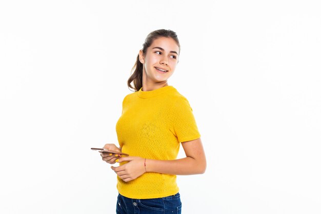 Young teen girl use of the cellphone isolated on white wall