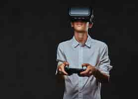 Free photo young teenager dressed in a white shirt wears virtual reality glasses and controls the quadcopter using the control remote.