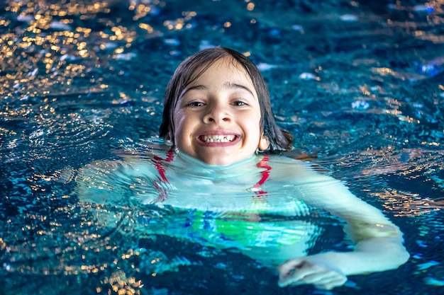 Free photo a young teenager girl in a swimsuit swimming in a blue pool