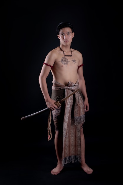 young THAILAND male warrior posing in a fighting stance with a sword